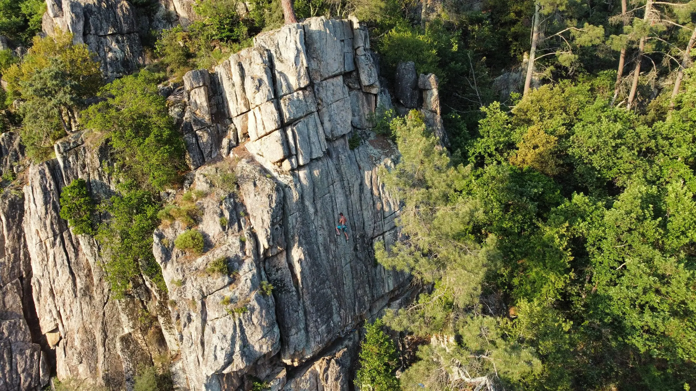 Grimpeur sur une voie de la falaise du Domaine Les Cabanes, vu depuis le ciel