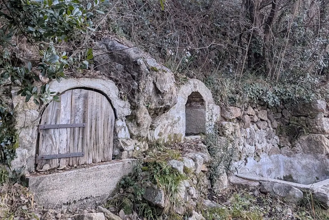 L'ancien lavoir en pierre du domaine, avec sa porte en bois et son bassin